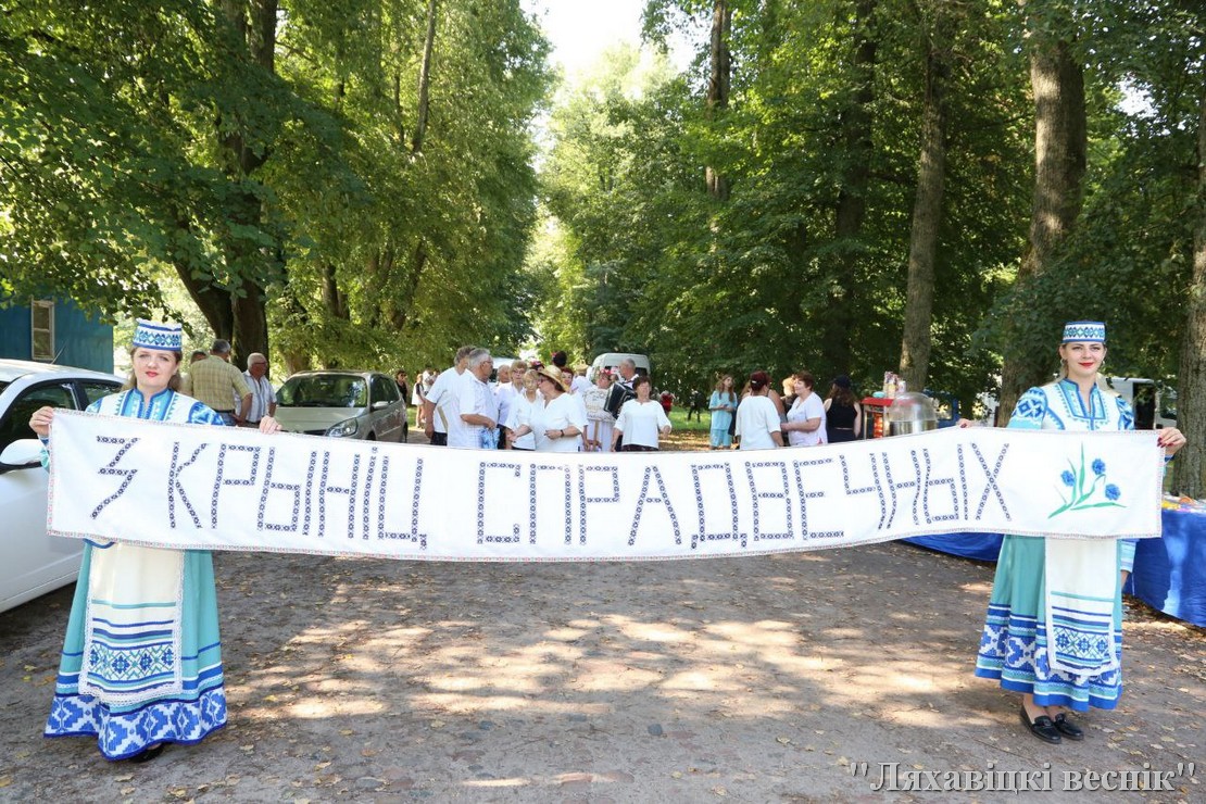 Участницы фестиваля в народных костюмах несут растяжку. 