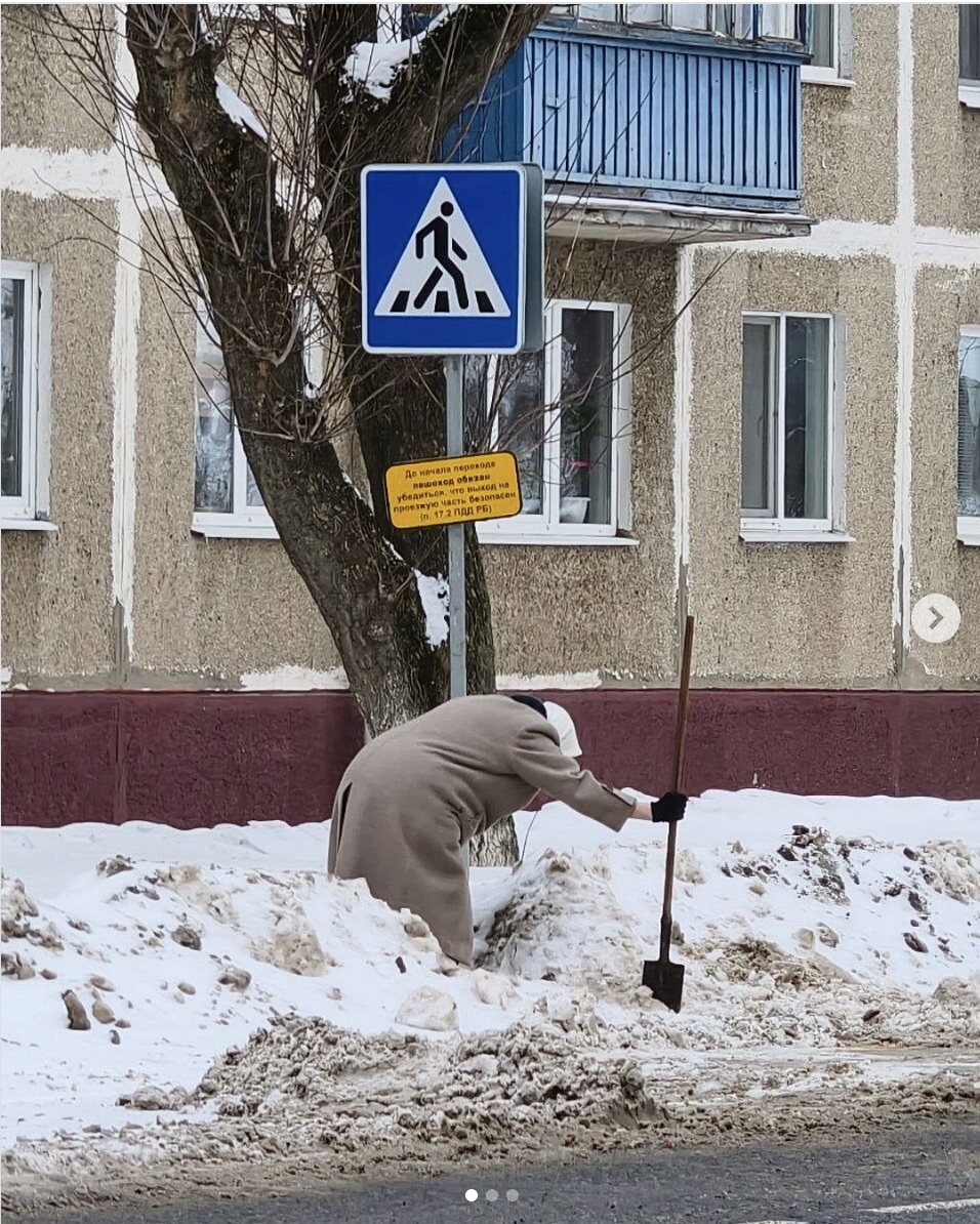 Пожилая женщина на пешеходном переходе в Слуцке чистит снег.